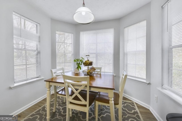 dining space featuring dark wood-type flooring and a textured ceiling