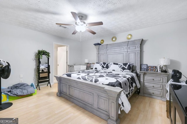 bedroom featuring ceiling fan, light hardwood / wood-style flooring, and a textured ceiling