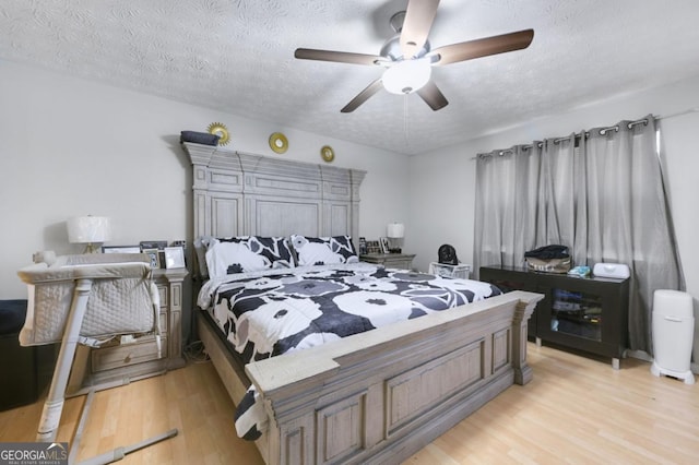 bedroom with ceiling fan, light hardwood / wood-style flooring, and a textured ceiling