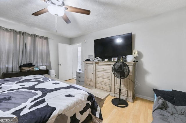 bedroom with ceiling fan, light hardwood / wood-style floors, and a textured ceiling