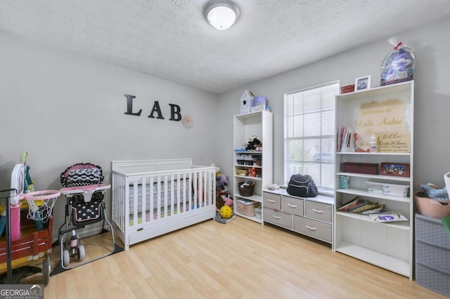 bedroom with light hardwood / wood-style floors and a textured ceiling