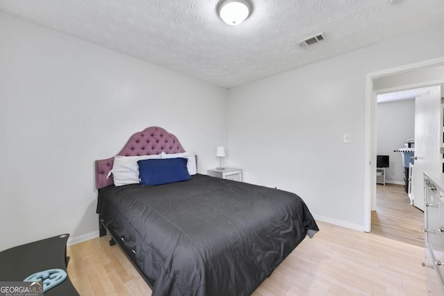 bedroom with light hardwood / wood-style floors and a textured ceiling