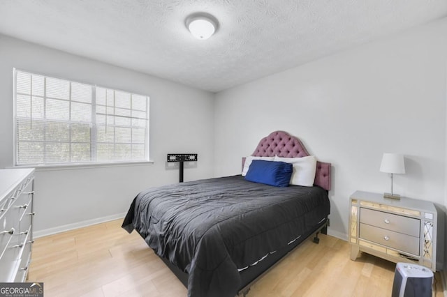 bedroom with a textured ceiling and light wood-type flooring