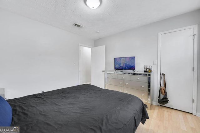 bedroom with a textured ceiling and light hardwood / wood-style floors