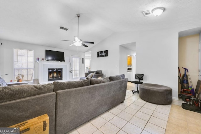 living room with lofted ceiling, a healthy amount of sunlight, a brick fireplace, and light tile patterned floors