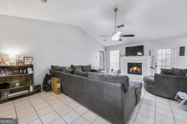 tiled living room with ceiling fan, a fireplace, and vaulted ceiling