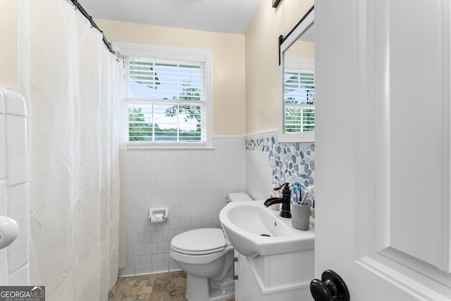 bathroom featuring plenty of natural light, toilet, vanity, and tile walls