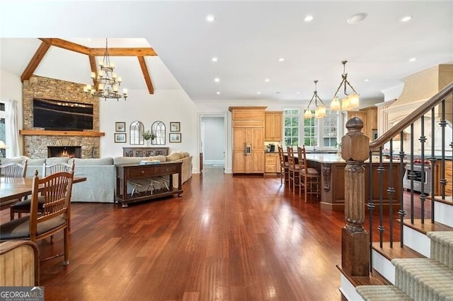 dining area featuring dark hardwood / wood-style flooring, vaulted ceiling with beams, a notable chandelier, and a fireplace