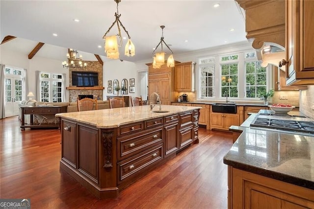 kitchen featuring decorative light fixtures, a large fireplace, decorative backsplash, a large island, and light stone countertops