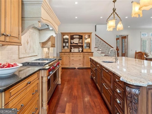 kitchen with dark stone countertops, sink, a spacious island, and premium range hood