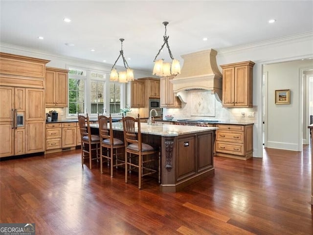 kitchen with decorative light fixtures, a kitchen bar, custom exhaust hood, light stone countertops, and a center island with sink