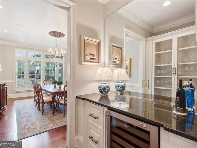 bar featuring white cabinetry, ornamental molding, beverage cooler, and decorative light fixtures