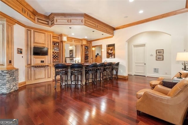 bar featuring dark hardwood / wood-style flooring, decorative light fixtures, crown molding, and light brown cabinets