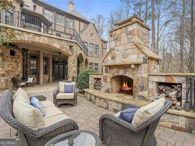 view of patio / terrace featuring a balcony and an outdoor stone fireplace