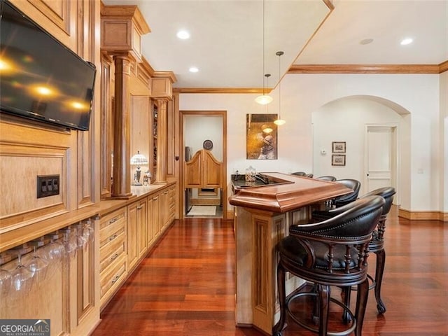 bar featuring crown molding, dark hardwood / wood-style floors, pendant lighting, and light brown cabinetry