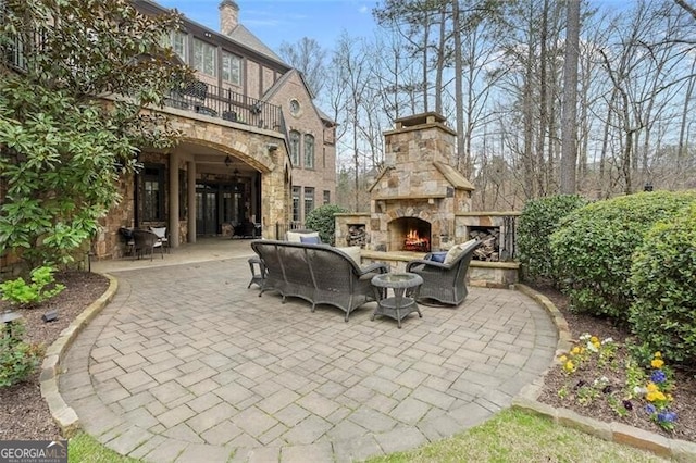 view of patio featuring a balcony and an outdoor living space with a fireplace