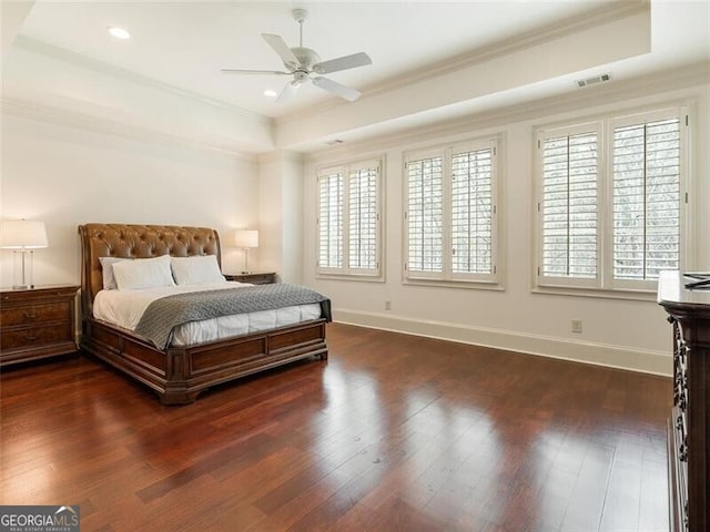 bedroom with a tray ceiling, dark hardwood / wood-style flooring, and multiple windows