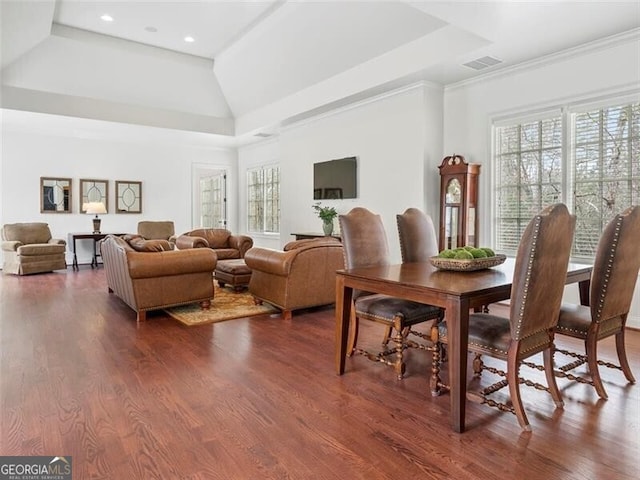 dining space with crown molding, dark hardwood / wood-style floors, and a raised ceiling