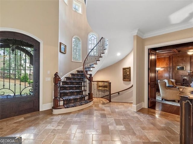 entrance foyer featuring ornamental molding, a high ceiling, and a wealth of natural light