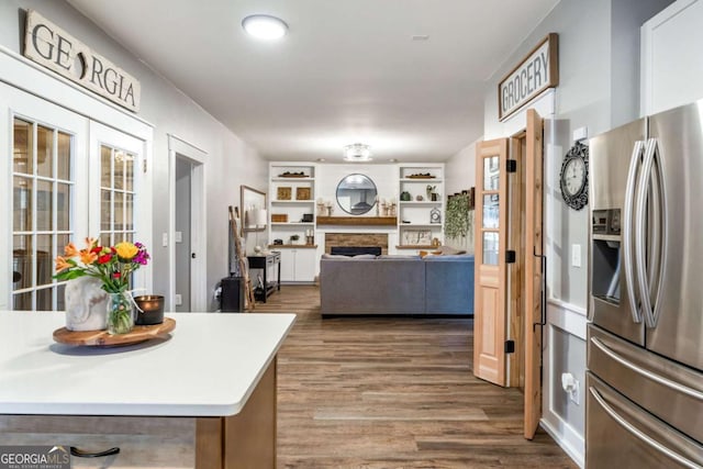 kitchen with a fireplace, hardwood / wood-style floors, and stainless steel refrigerator with ice dispenser