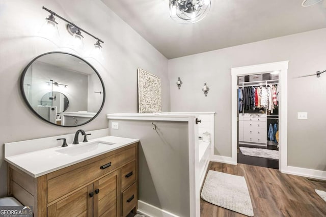 bathroom with hardwood / wood-style flooring, vanity, and a tub to relax in