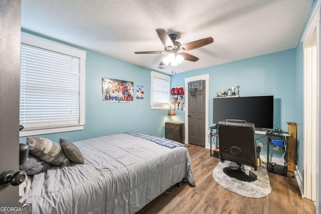 bedroom with hardwood / wood-style flooring, ceiling fan, and a textured ceiling