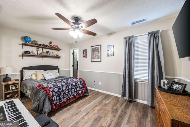 bedroom with ceiling fan, wood-type flooring, and a textured ceiling