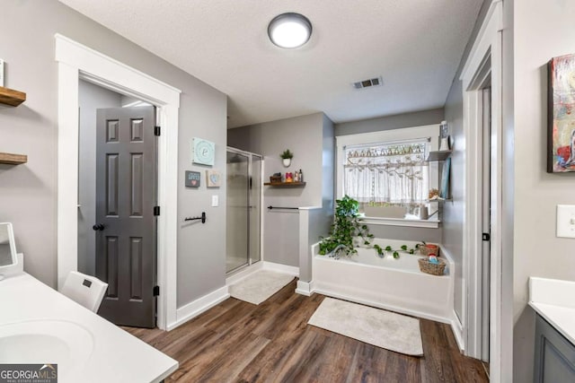 bathroom featuring plus walk in shower, vanity, a textured ceiling, and hardwood / wood-style floors