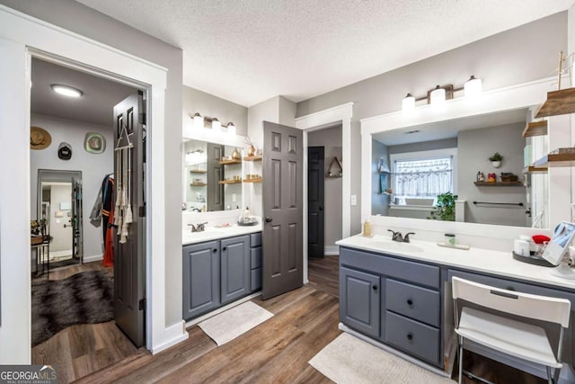 bathroom with wood-type flooring, vanity, and a textured ceiling