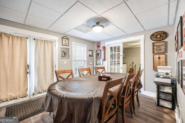 dining room featuring french doors, dark hardwood / wood-style flooring, and a drop ceiling