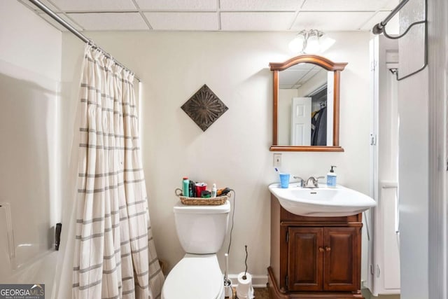 bathroom with toilet, vanity, walk in shower, and a drop ceiling