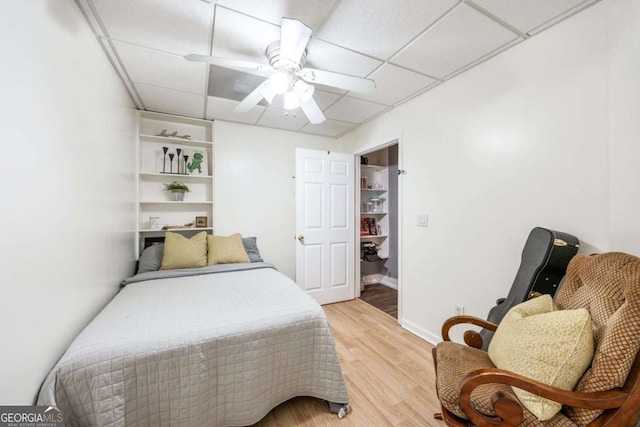 bedroom with hardwood / wood-style flooring, ceiling fan, and a paneled ceiling