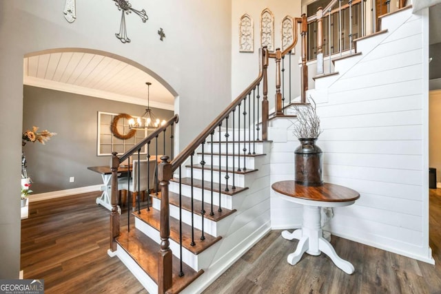 stairway with ornamental molding, wooden ceiling, an inviting chandelier, and hardwood / wood-style floors