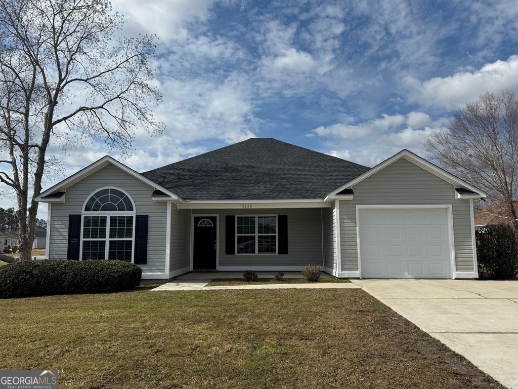 ranch-style house featuring a garage and a front lawn