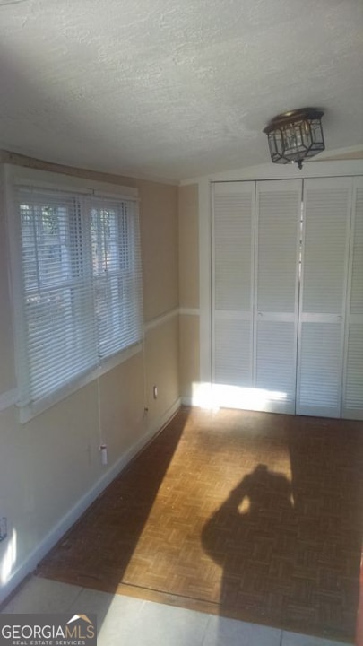 unfurnished room featuring parquet floors and a textured ceiling