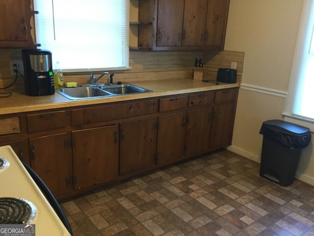 kitchen featuring sink, a wealth of natural light, dark brown cabinetry, and decorative backsplash