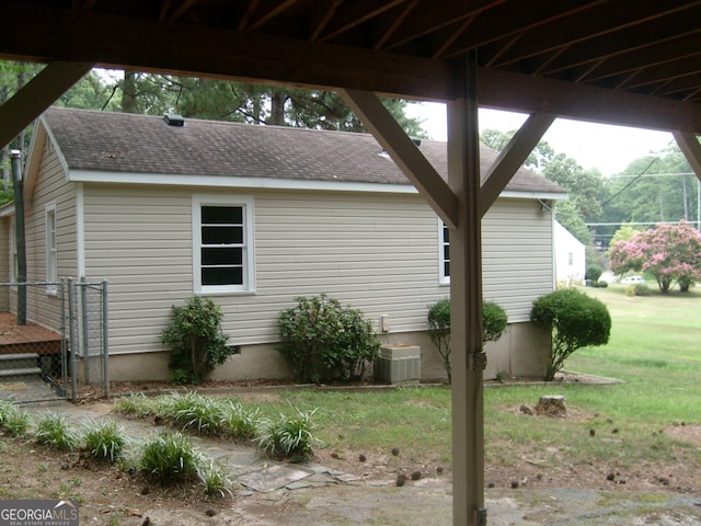 view of side of property with a yard and central AC