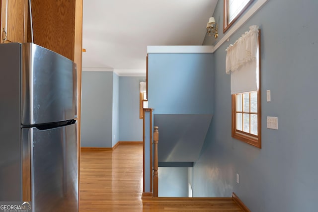 kitchen with crown molding, stainless steel fridge, and light wood-type flooring