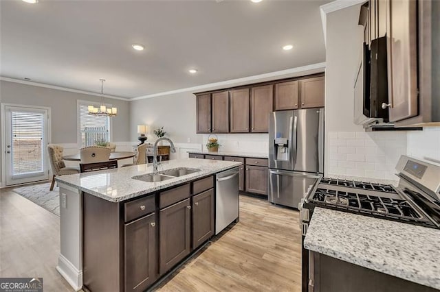 kitchen featuring sink, crown molding, appliances with stainless steel finishes, hanging light fixtures, and light stone counters