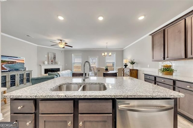 kitchen with light stone counters, sink, dark brown cabinets, and dishwasher