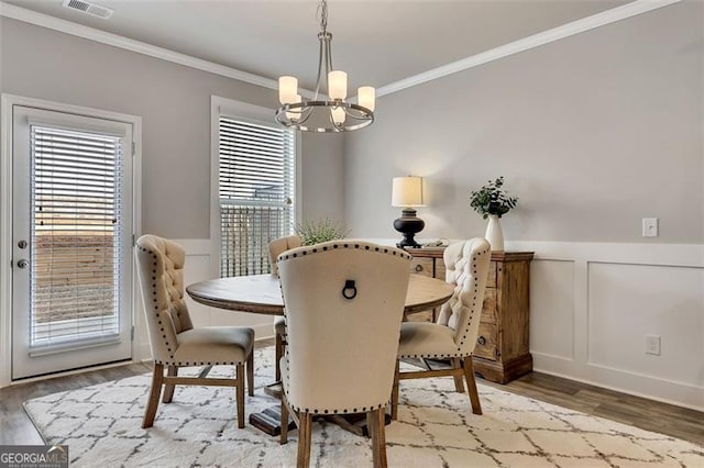 dining area featuring ornamental molding, wood-type flooring, and an inviting chandelier