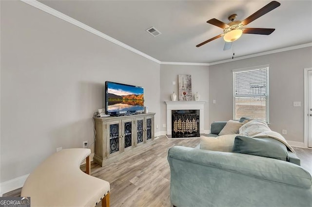 living room with ornamental molding, ceiling fan, and light hardwood / wood-style floors