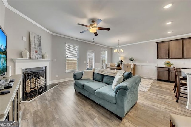 living room featuring ornamental molding, ceiling fan with notable chandelier, and light hardwood / wood-style flooring