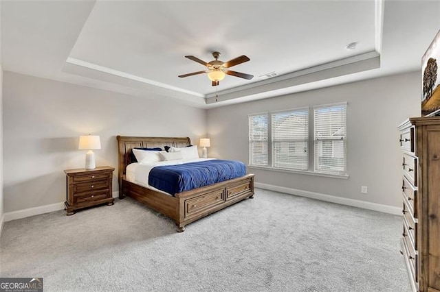 bedroom with ceiling fan, a tray ceiling, and light carpet