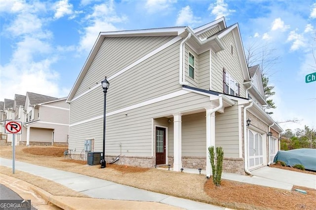 view of property exterior with a garage and central AC unit