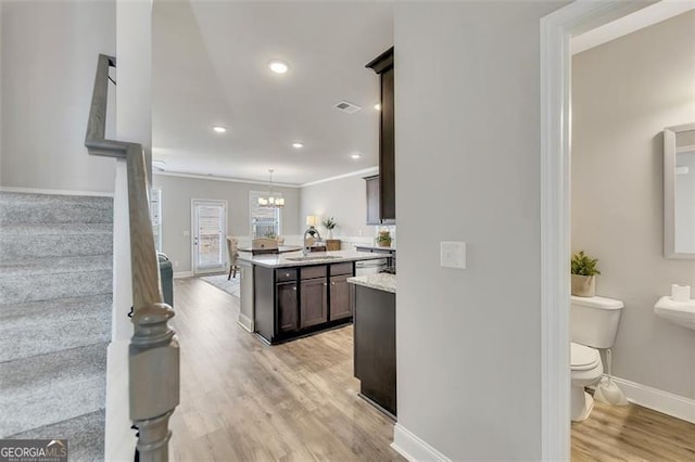 kitchen featuring sink, dark brown cabinets, a notable chandelier, decorative light fixtures, and light wood-type flooring