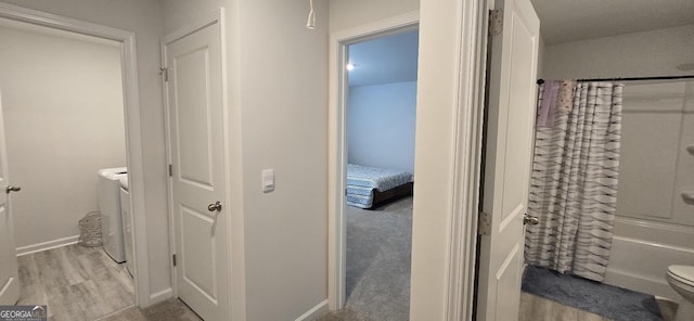 bathroom with shower / bath combination with curtain, toilet, hardwood / wood-style floors, and washer and dryer