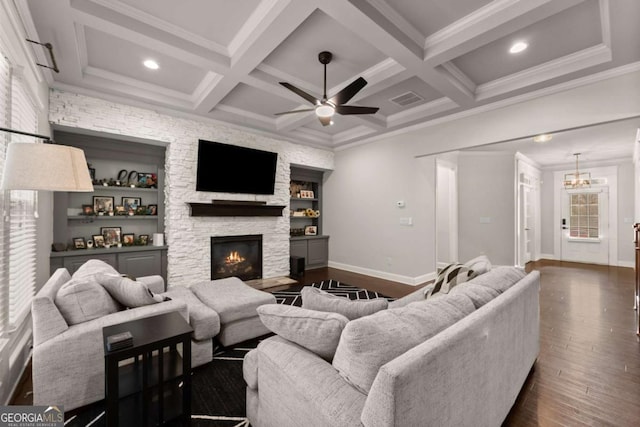 living room featuring coffered ceiling, a stone fireplace, dark hardwood / wood-style flooring, beamed ceiling, and ceiling fan with notable chandelier