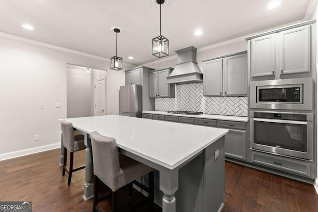 kitchen with decorative light fixtures, gray cabinets, premium range hood, and appliances with stainless steel finishes