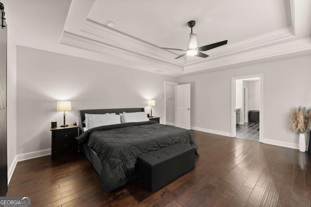 bedroom featuring dark wood-type flooring, ornamental molding, a barn door, and a raised ceiling